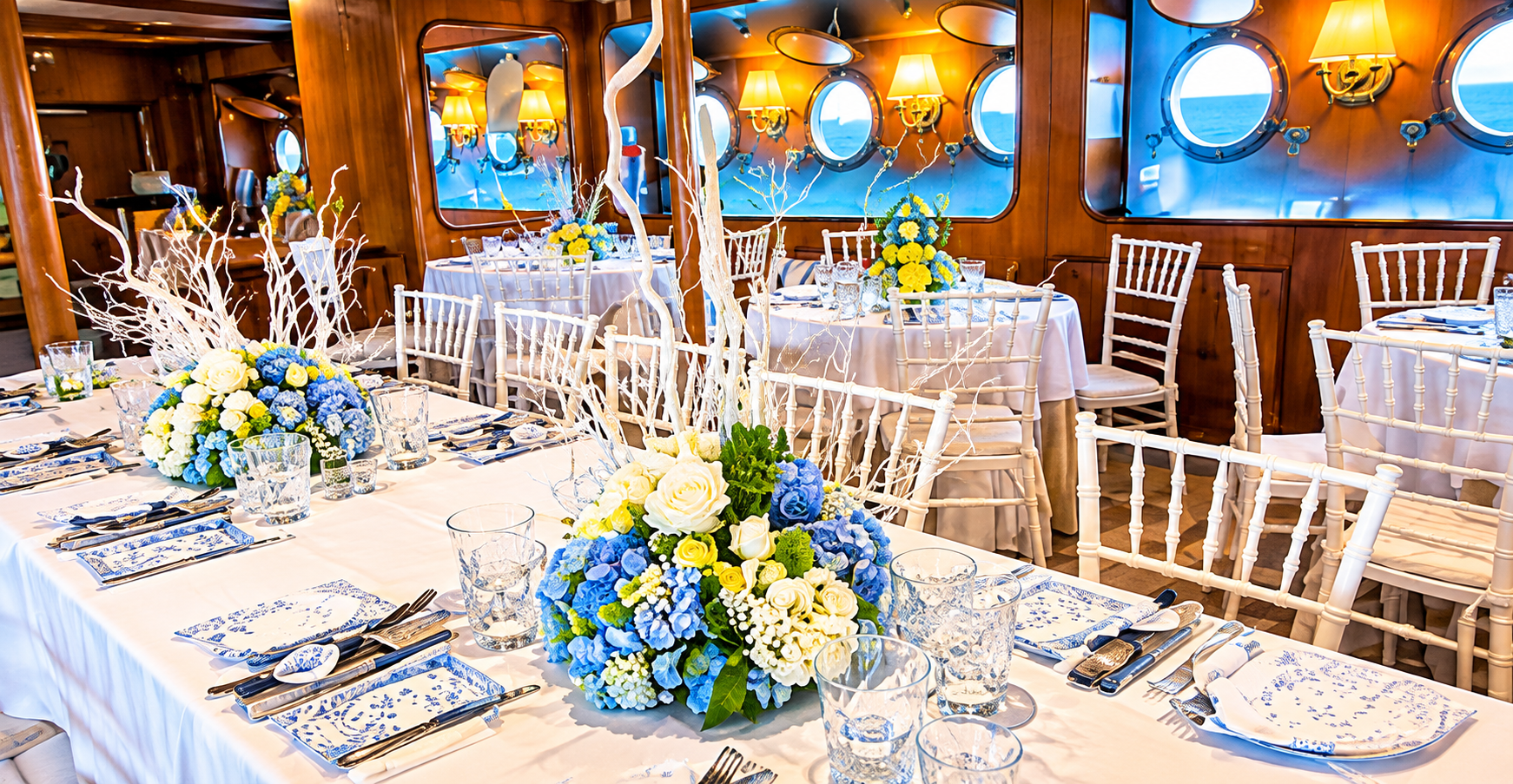 Tavola elegante apparecchiata nella sala ristorante del Veliero Tortuga con decorazioni floreali azzurre e bianche